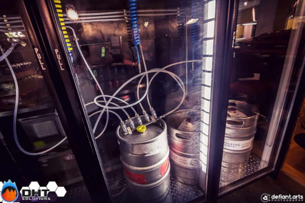 Kegs connected inside the glass-door keg fridge behind the bar