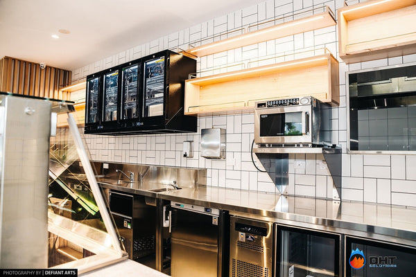 Wall-mounted glass-door fridges above the coffee bench, with a microwave, ice maker and under-counter refrigeration below