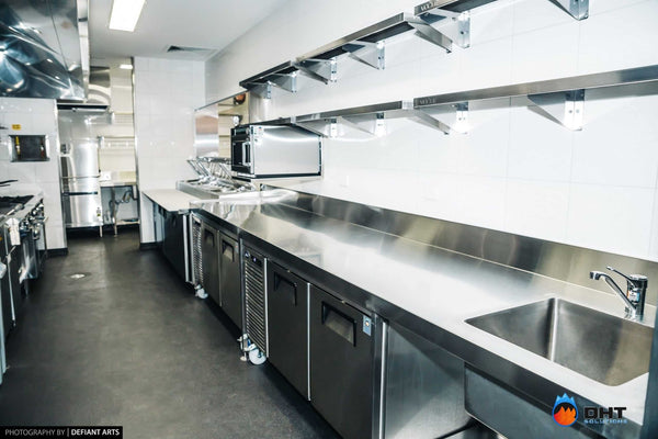 The galley kitchen line, with under-counter refrigeration and wall shelving the length of the bench
