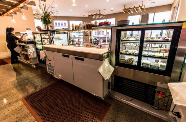 The front counter with the refrigerated cake display and sandwich prep fridge