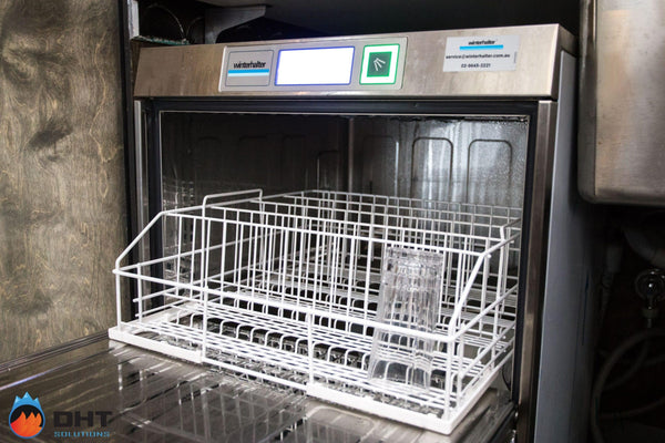 Winterhalter under-counter glasswasher open with a rack of glasses in the bar