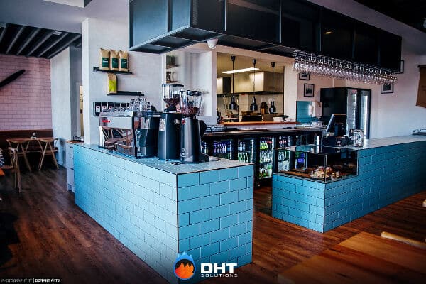 Wide view of the History Cafe Essendon interior, with a blue-tiled coffee bar in the foreground and the main bar behind