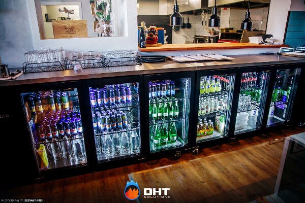 A run of five glass-door Williams back bar fridges stocked with bottled drinks beneath the bar counter