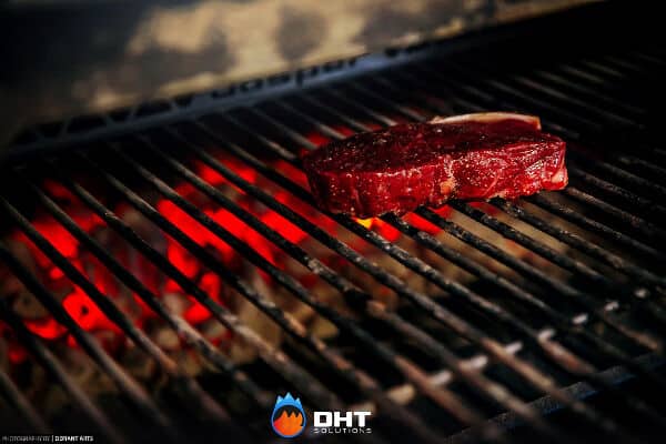 A thick cut steak searing over glowing coals on the grill bars of the Josper charcoal oven