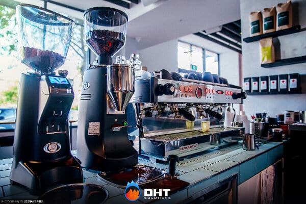 Two conical coffee grinders beside a multi-group espresso machine on the cafe's coffee bar