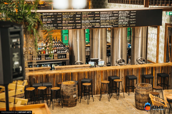 The main bar under the tap list, with brewery fermenters behind
