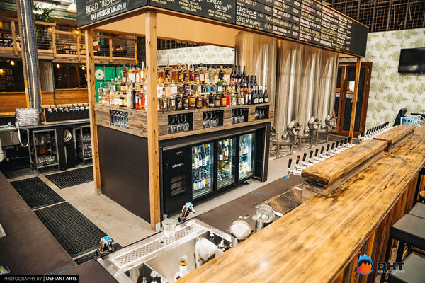Williams glass-door back bar fridge beneath the spirits shelf, with the tap bank along the counter