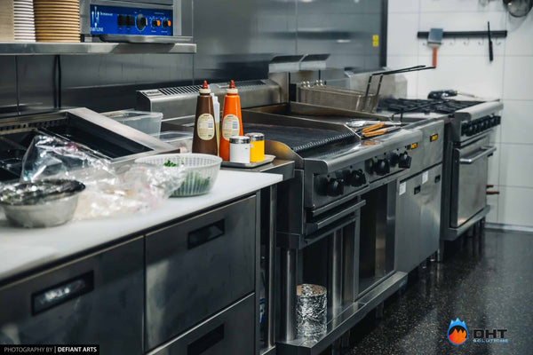 The cooking line with char grill, fryers and gas burners behind the prep bench