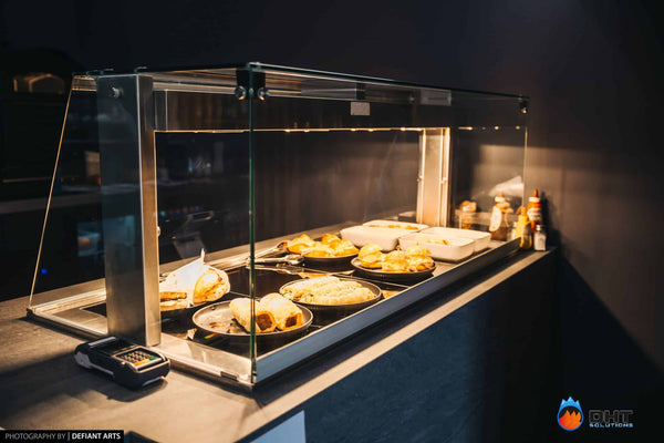 Heated food display on the counter holding pies and sausage rolls